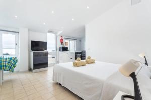 a white bedroom with a large bed and a kitchen at BLife Benya private apartment in Faro