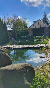 a pond with a wooden walkway in front of a house at Zakątek Łąkowa in Suwałki