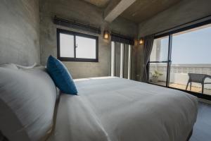 1 dormitorio con 1 cama blanca grande con almohadas azules en Serendipity House澎湖望安島 en Wang-an