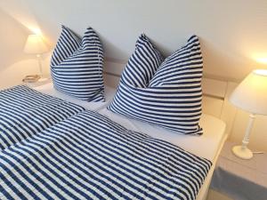 3 blaue und weiße gestreifte Kissen auf einem Bett in der Unterkunft Ferienwohnung Südpol, Pellworm in Pellworm