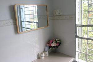 un espejo en el baño con un jarrón de flores en 79/10 Tran Phu House, en Can Tho