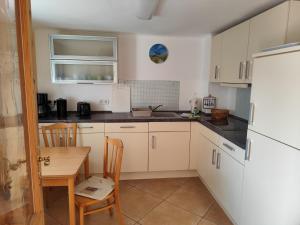 a kitchen with white cabinets and a table and a refrigerator at Sonnengarten in Ueckeritz