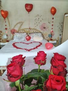 a bed with red roses and red heart balloons at Le Cocon des Layes in Les Essarts-le-Roi