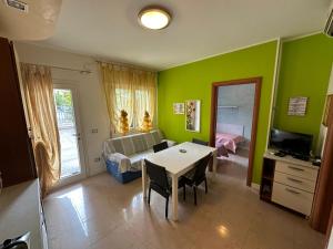 a living room with green walls and a table and a couch at Appartamenti Levante - Agenzia Cocal in Caorle