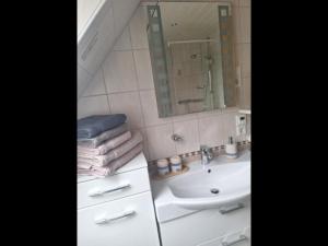 ein weißes Badezimmer mit einem Waschbecken und einem Spiegel in der Unterkunft Ferienwohnung Südpol, Pellworm in Pellworm