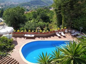 a large blue swimming pool in a yard with chairs at Villa Elvira in Pellezzano