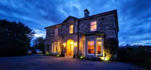 an old stone house with its lights on at The Pines Guest House in Elgin