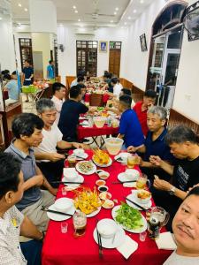 een groep mensen die aan een lange tafel eten bij Hai Hoa Hotel in Cửa Lô