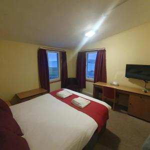 um quarto com uma cama, uma secretária e uma televisão em The Brae Hotel em Brae