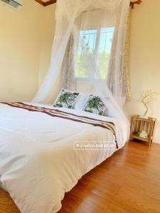 a bedroom with a white bed with a window at Baan Hug Na in Ban Khao Chakan