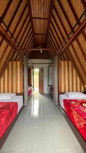 a bedroom with two beds in a room with a wooden ceiling at Puri Pilihani Hostel in Munduk
