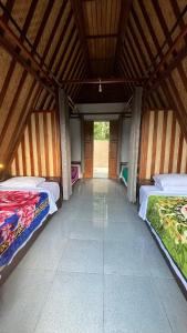 two beds in a room with a wooden ceiling at Puri Pilihani Hostel in Munduk