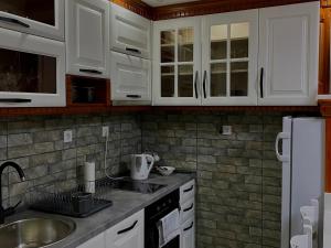 una cocina con armarios blancos y fregadero en Apartment LAKEVIEW en Pluzine