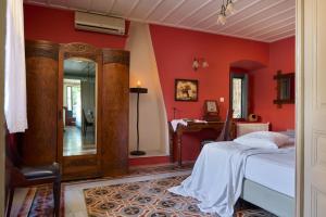 - une chambre avec des murs rouges, un lit et un miroir dans l'établissement Sto Roloi Island Houses, à Poros