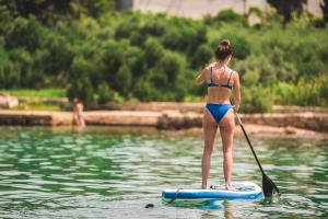 a woman in a bikini on a paddle board in the water at Rhythm Floating Hostel - Split in Split