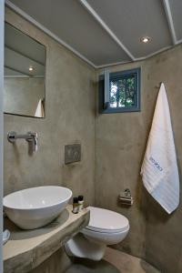 a bathroom with a sink and a toilet and a mirror at Sto Roloi Island Houses in Poros