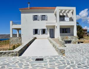 a white house with a walkway in front of it at Merabello Villas Karystos in Karistos