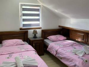 two beds in a bedroom with pink sheets and a window at Apartment LAKEVIEW in Pluzine