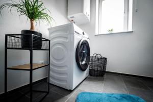 a white washing machine in a room with a plant at Schicke Wohnung in Seenähe! 