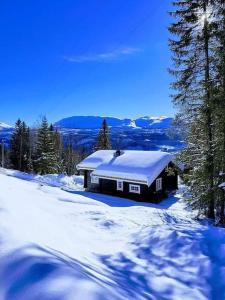 una cabaña en la nieve con techo cubierto de nieve en Flott fjellhytte ned fantastisk utsikt., 
