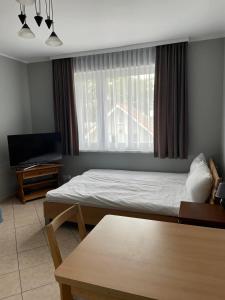 een slaapkamer met een bed, een tafel en een raam bij Mieszkanie przy promenadzie Trzęsacz in Trzęsacz