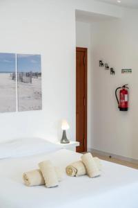a white bedroom with a bed with three towels at BLife Benya private apartment in Faro