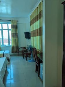 Habitación con cama, escritorio y TV. en Đại An Hotel N, en Ninh Binh