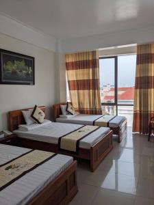 1 dormitorio con 3 camas y balcón en Đại An Hotel N, en Ninh Binh