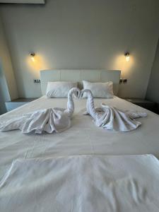 two white swans laying on top of a bed at Aqua Mare Luxury Apartments in Paralia Katerinis