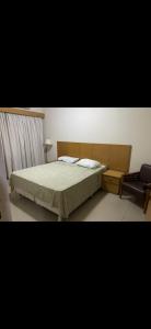 a bedroom with a bed and a chair at Plaza Flat in Ribeirão Preto