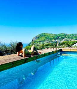 Eine Frau im Bikini, die auf einem Steg im Pool liegt. in der Unterkunft Wanderlust in Piano di Sorrento
