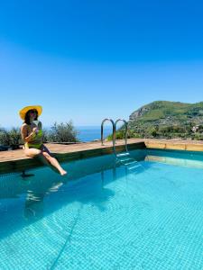 une femme dans un chapeau assise à côté d'une piscine dans l'établissement Wanderlust, à Piano di Sorrento