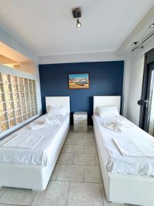 Aqua Mare Luxury Apartments في باراليا كاتيرينّيس: سريرين في غرفة ذات جدار أزرق
