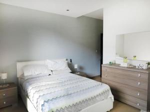 a bedroom with a large white bed and a dresser at Seaside Serenity: Mellieha Gem in Mellieħa
