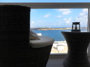 a room with a window with a chair and a table at Seaside Serenity: Mellieha Gem in Mellieħa