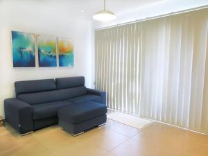 a living room with a blue couch and a window at Seaside Serenity: Mellieha Gem in Mellieħa