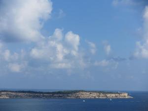an island in the ocean under a cloudy sky at Seaside Serenity: Mellieha Gem in Mellieħa