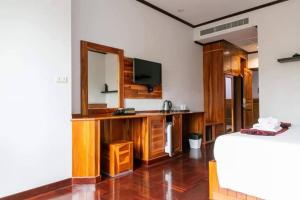a living room with a tv and a wooden entertainment center at Sky View Hotel Buriram in Buriram