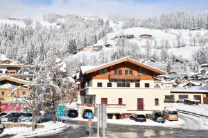 a snow covered village with cars parked in front of a building at Appartements neben der Gondelbahn - Haus Süd in Brixen im Thale