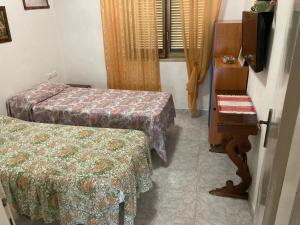 リド・ディ・フォンディにあるcasa Ginevraのベッド2台とテーブルがある小さな部屋 +4枚の写真