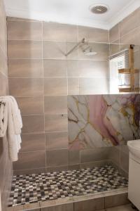 a bathroom with a shower with a tiled wall at Neapolitan Guesthouse in Alberton