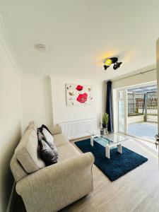 uma sala de estar com um sofá e uma mesa de vidro em Deluxe Bungalow em Longham