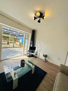 uma sala de estar com uma mesa de vidro e um sofá em Deluxe Bungalow em Longham