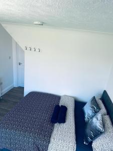 uma cama com almofadas azuis num quarto em Deluxe Bungalow em Longham