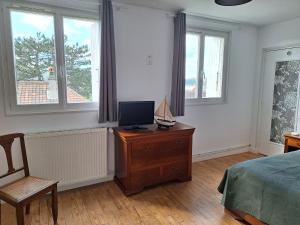 1 dormitorio con cama y vestidor con TV en La fleur du soleil, en Trouville-sur-Mer