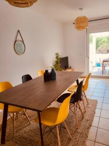 a dining room with a wooden table and yellow chairs at Sand, Water & Sun House in Vila Nova De Cacela