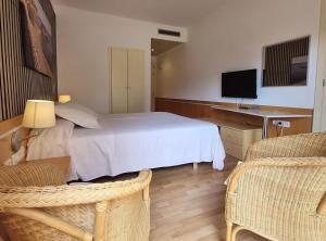 a bedroom with a white bed and two chairs at Hotel Ancora in Palamós