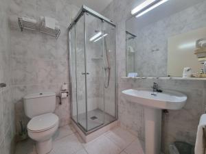 a bathroom with a shower and a toilet and a sink at Hotel Ancora in Palamós