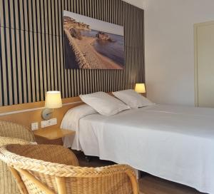a hotel room with two beds and a chair at Hotel Ancora in Palamós