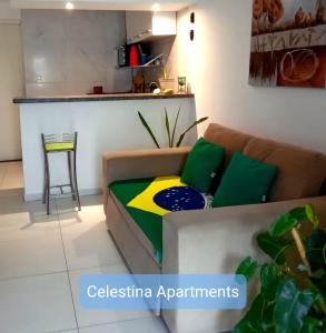 a couch with green and yellow pillows in a living room at APARTAMENTO NO CENTRO DE BUZIOS in Búzios